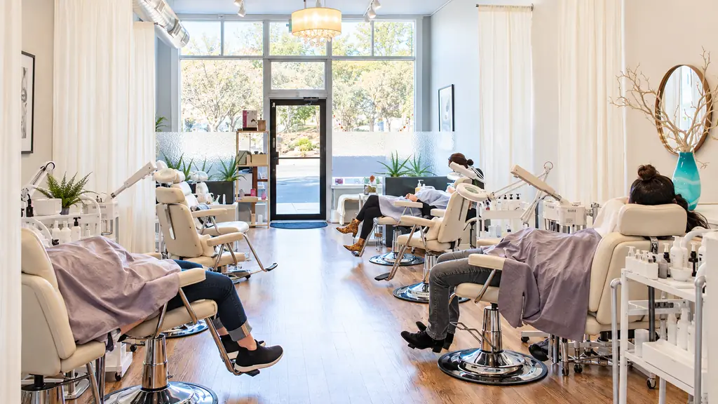 The open room at Glow Facial Bar: a row of white chairs on a hardwood floor, daylight through the front glass, clients reclined